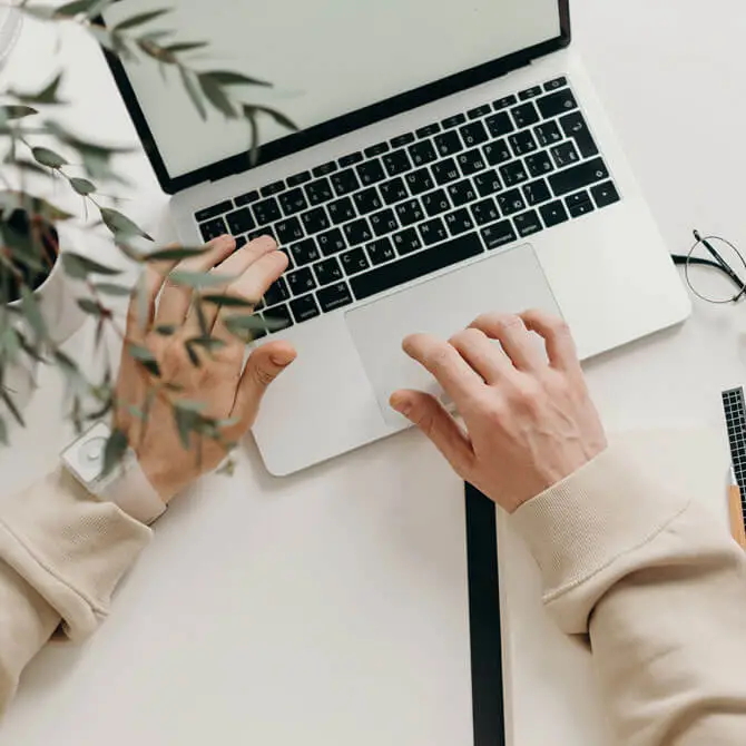 Two hands hover laptop.